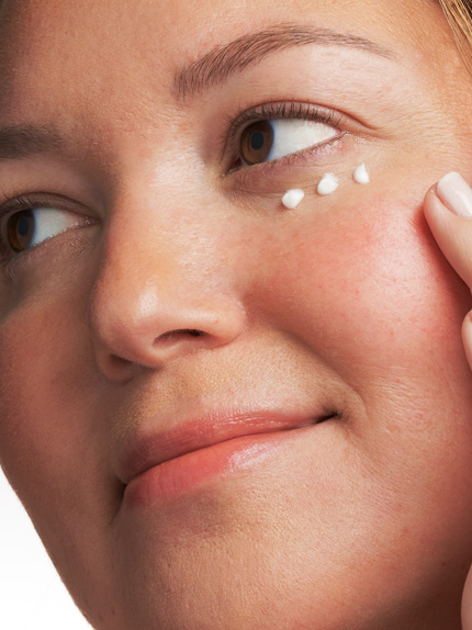 Kvinna som har applicerat sin ögonkräm på tre punkter under ögat.