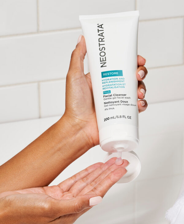 30135_restore_pha_facial_cleanser_v3_2.jpg Neostrata produkt trycks ut i en hand mot en bakrund som liknar ett badrum.