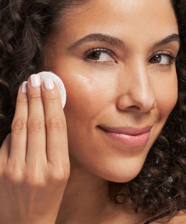 30145_neostrata_clarify_oily_skin_solution_v4.jpg Kvinna applicerar produkt på sin kind med en bomullspad.