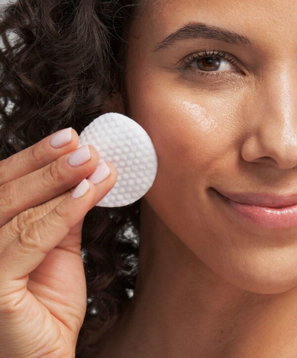 30134_neo_smooth_surface_glycolic_peel_v4.jpg Kvinna kollar in i kameran och håller upp en bomullspad intill ansiktet.