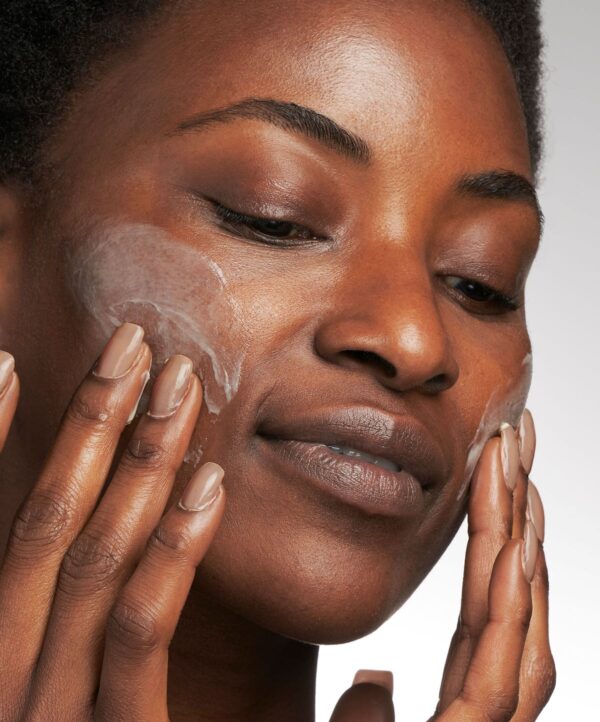 30160_neostrata_pigment_controller_v4.jpg Kvinna applicerar produkt på kinderna med sina händer.